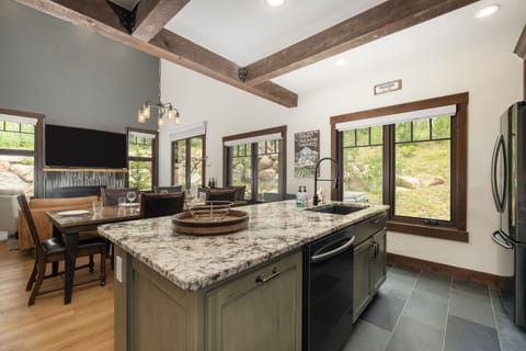 Your open kitchen features granite countertops, rustic beams, and stunning natural views through large windows.