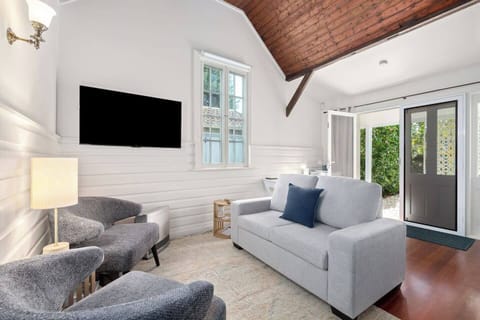 The cosy living area invites relaxation with a wall-mounted TV, plush armchairs, and a two-seater sofa.