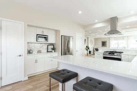 This kitchen features white cabinetry, stainless steel appliances, and a spacious island with bar seating. The stylish backsplash adds a subtle texture, while recessed lighting enhances the airy and open feel. Perfect for cooking and entertaining!️
