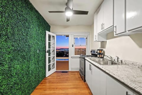 This spacious kitchen is equipped with the basics—stainless steel range and sink, white cupboards, and a light-colored counter. The glass window and French door showcase the beauty of the early evening.