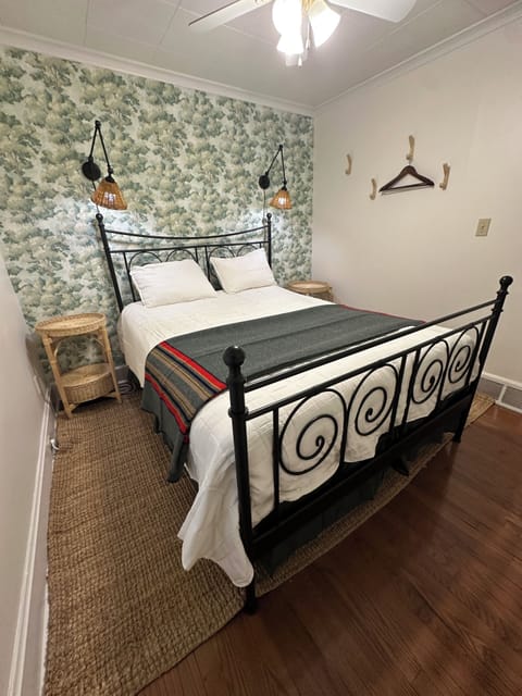 The guest bedroom has wallpaper, scones and hanging area for clothes.