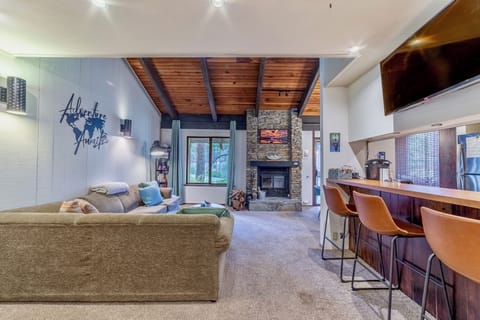 Open living room w/ vaulted ceilings and TV over bar.