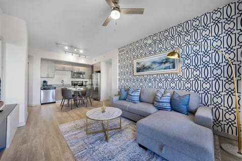 Stylish Living Space-Bright and inviting living area with a modern sectional, bold accent wall, and chic décor. Perfect for relaxing or entertaining with an open layout leading to the kitchen and dining area.