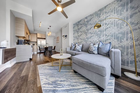 Stylish Living Space-Bright and inviting living area with a modern sectional, bold accent wall, and chic décor. Perfect for relaxing or entertaining with an open layout leading to the kitchen and dining area.