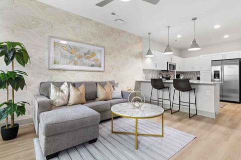 Modern Open-Concept Living-Bright and stylish living room with plush seating, abstract art, and natural accents flows seamlessly into a sleek kitchen with stainless steel appliances and breakfast bar seating.