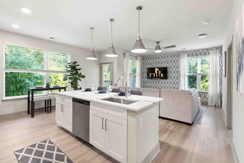 Bright Open Kitchen & Living Area-Modern kitchen with island seating, stainless appliances, and pendant lighting flows into a cozy living space with large windows and natural light, creating a warm and inviting atmosphere.