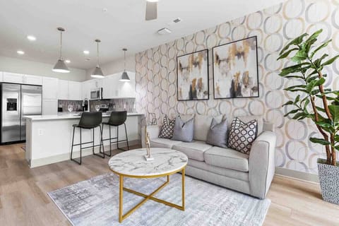 Modern Open-Concept Living-Bright and stylish living area with cozy sofa, chic décor, and open kitchen featuring stainless appliances and breakfast bar. A perfect blend of comfort and modern design for a relaxing stay.