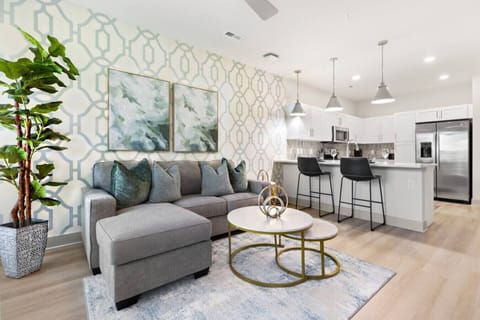 Modern Open-Concept Living-Bright and stylish living area with cozy sofa, chic décor, and open kitchen featuring stainless appliances and breakfast bar. A perfect blend of comfort and modern design for a relaxing stay.