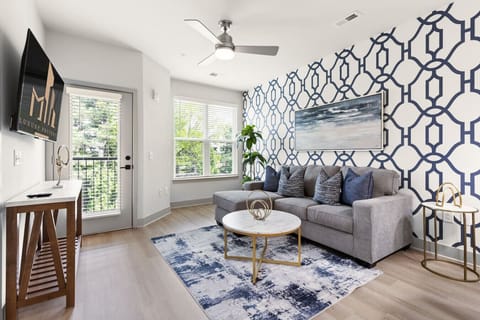 Cozy Living Room Retreat-Bright and airy lounge with a plush sofa, modern artwork, and large windows letting in natural light. Features a stylish coffee table, soft rug, and TV for a comfortable and inviting stay.