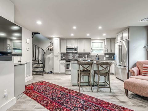 Prepare your favorite meals in this modern and fully-equipped kitchen. It features sleek, light-colored cabinetry, stainless steel appliances, and a convenient kitchen island with seating for two.