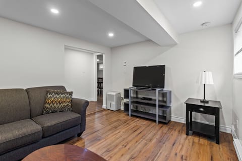 Relaxing Living Room: Comfortable lounge area featuring a plush sofa, flat-screen TV, and warm wood flooring—the perfect spot to unwind.