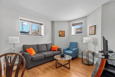 Relax in this modern living space featuring a comfortable sofa, accent chair, and large windows that fill the room with natural light. Perfect for unwinding after a day of exploring.