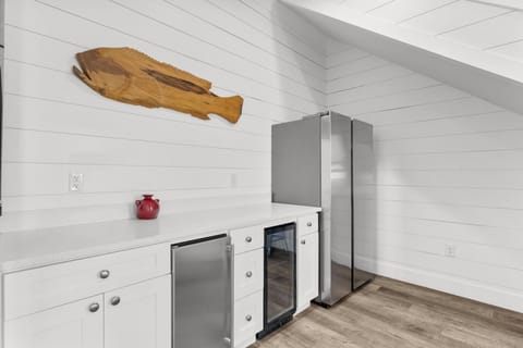 Modern kitchenette with sleek appliances and unique wooden fish art.