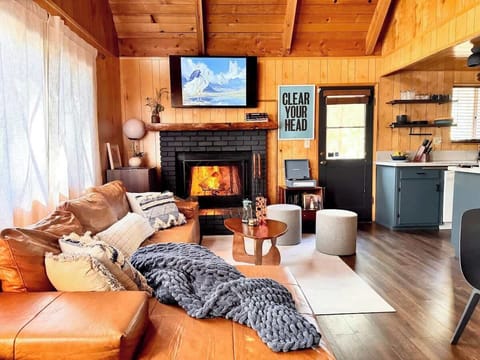 Modern rustic A-frame living room with retro cabin vibes and crackling fireplace