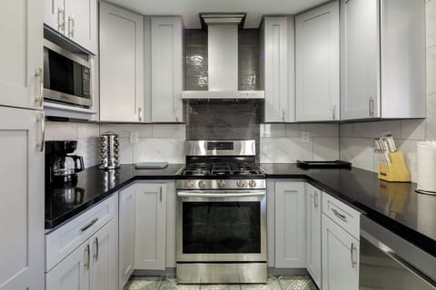 Modern kitchen with deep stainless sink, pull-down faucet, and black quartz counters.