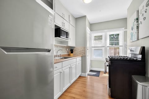 Functional kitchen setup with stove, full sink, microwave, and cooking utensils