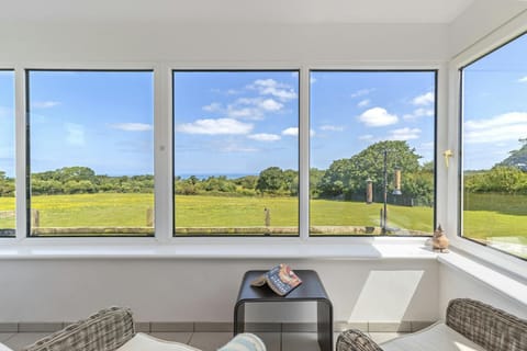 Conservatory with chairs and views over the fields towards the sea
