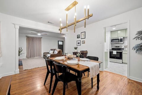 Spacious dining room with seating for four to six  (including bench) under a modern chandelier