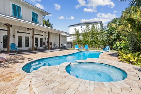 Private, fully fenced backyard featuring a custom heated pool (3ft–6ft deep) with an attached hot tub, paver pool deck with lounge chairs, patio with porch swing, bistro table, and a variety of comfortable outdoor seating options.