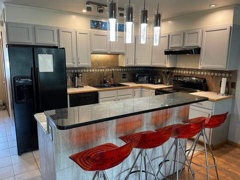 Chef's kitchen with microwave, coffee maker, toaster, utensils, plates, & pans.