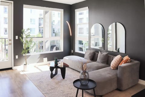 Spacious living room featuring a cozy L-shaped sofa, a full-size air mattress, and a 65" Smart TV with preloaded access to Netflix, Hulu, and Disney+, all set up for your enjoyment.