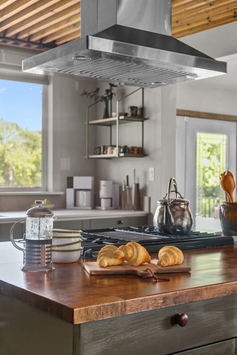 In the heart of the kitchen, the gas stove brings both warmth and function to the space. Its sleek design beneath the bold vent hood makes cooking feel effortless, whether you’re preparing a quick breakfast or a family-style dinner.