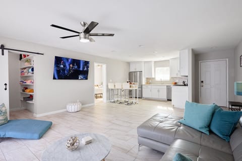 Open-concept living room with a cozy sectional, Smart TV, and sliding glass doors filling the space with natural light.