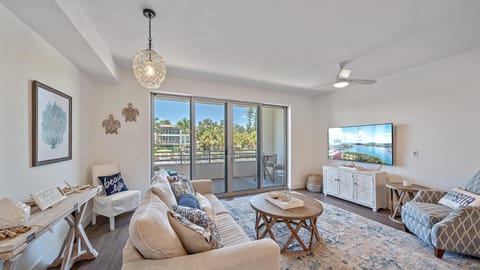Unwind in the beautifully decorated coastal living room, featuring a comfortable sofa, large Smart TV, and direct access to your scenic balcony.