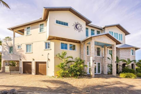 Elegant three-story coastal home with grand stone entry, tropical landscaping