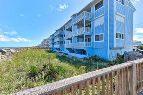 Colorful coastal homes line the shore with private balconies overlooking dunes and ocean access just steps away.