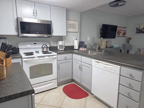 Kitchen features pans, utensils, crockpot, dishware.  