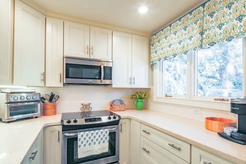The renovated kitchen features stainless steel appliances, a double window and white cabinetry.