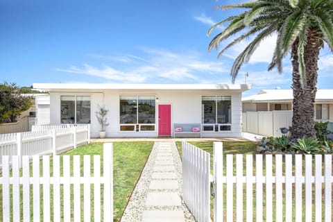 Arrive to bright beach-house charm, framed by palms and a cheerful pop of colour that signals you’ve reached the coast.
