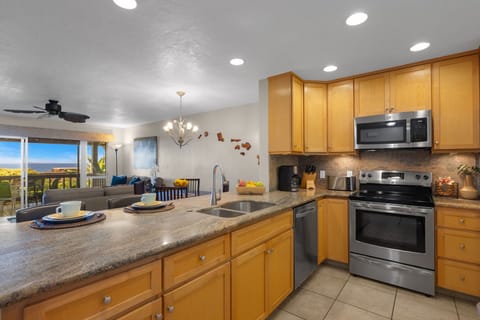 Fully equipped kitchen featuring stainless steel appliances, spacious countertops, and a view into the dining area