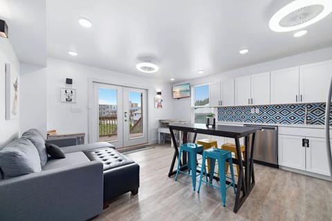Modern and elegant living space featuring a cozy gray sofa, colorful bar stools, and a view from the patio doors