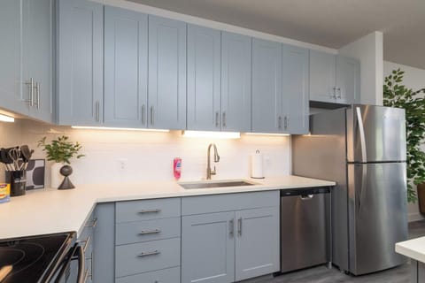 Compact kitchen fully stocked with all essentials and sleek stainless steel appliances—everything you need in a cozy space.