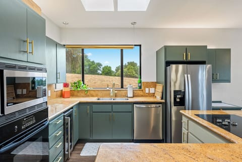 Create culinary magic in this stylish space, featuring unique sage green cabinetry, golden-brown granite countertops, and a wide window overlooking the beautiful rolling hills.