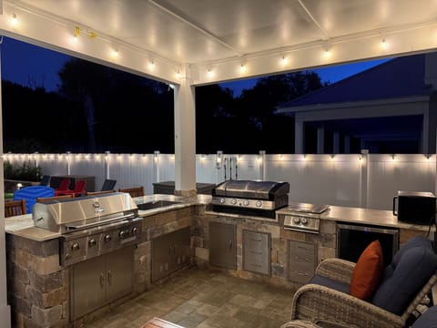 A fully equipped outdoor kitchen w/ bbq grill, sink, griddle, burner, fridge


