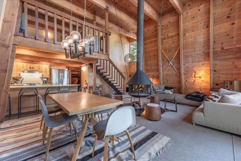 Open living room with comfy furnishings, dining area, and a floating wood burning fireplace!