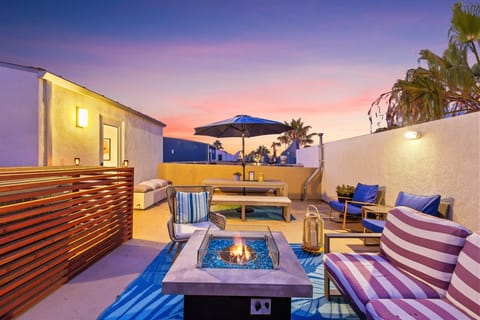 Golden hour on your private rooftop, with a fire pit, lounge seating, and an umbrella-shaded table for sunset dinners