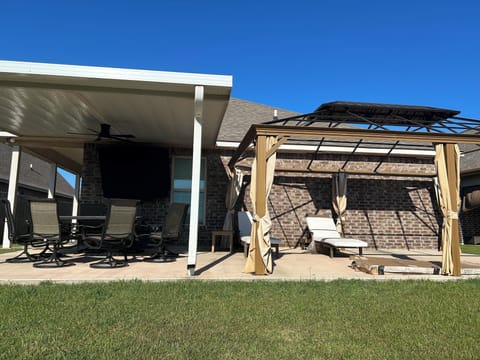 Outdoor terrace area with tv, dining table that fits 8, and lounging chairs