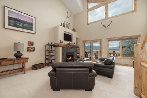 Unwind by the crackling fireplace while mountain views stretch beyond the windows in this cozy living room.