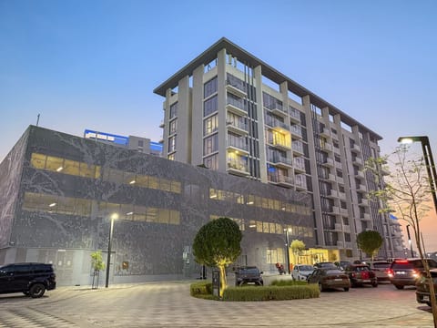 Stylish mid-rise building with balconies and parking area at sunset.