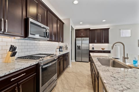 Cook and gather in the modern kitchen, featuring a gas stovetop, microwave, and a large granite island perfect for meal prep or casual dining.