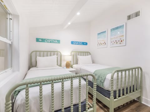 Drift off in airy twin beds under calming beach art.