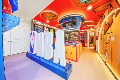Experience a lively game room celebrating basketball culture, with bold red ceilings and vibrant NBA decor. Enjoy a playful atmosphere filled with dynamic lighting and colorful accents, ideal for both entertainment and relaxation.