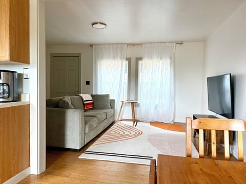 Cozy light living room with soft throws, smart TV, books, games and original art