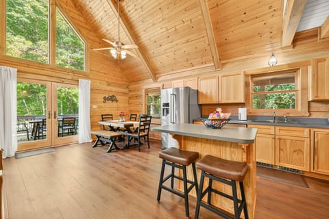 Sunlit kitchen and dining area with vaulted ceilings and forest views