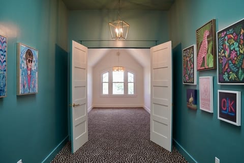 Leopard print carpet and bold gallery walls lead into a bright, vaulted room. A striking mix of pattern and color brings unexpected personality to this space, making the walk into the room part of the experience at Parkway House Goshen.