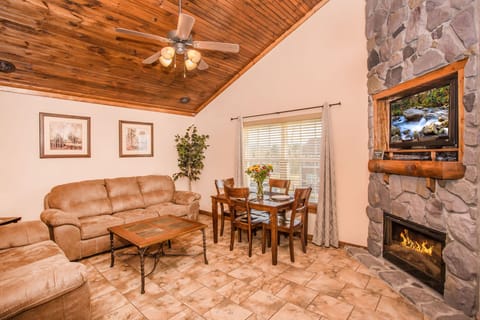 Living room with sofa seating, stone fireplace, and vaulted wood ceiling.